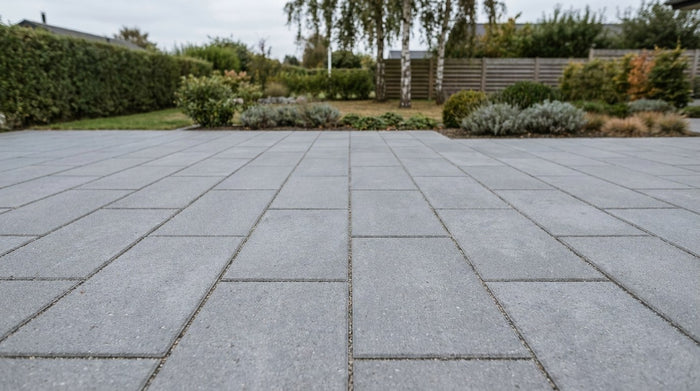 En moderne indkørsel belagt med store 60x90 cm soldaterfliser i beton, der er lagt med korrekte fuger og et stærkt bærelag.