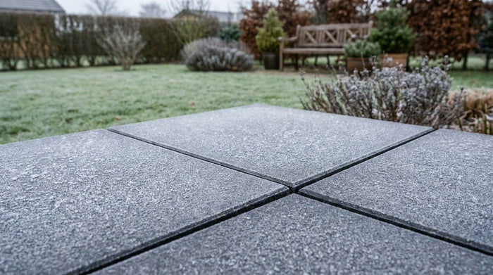 En smuk og moderne terrasse anlagt med store, mørke frostsikre keramiske fliser, der forlænger stuens gulv ud i haven.