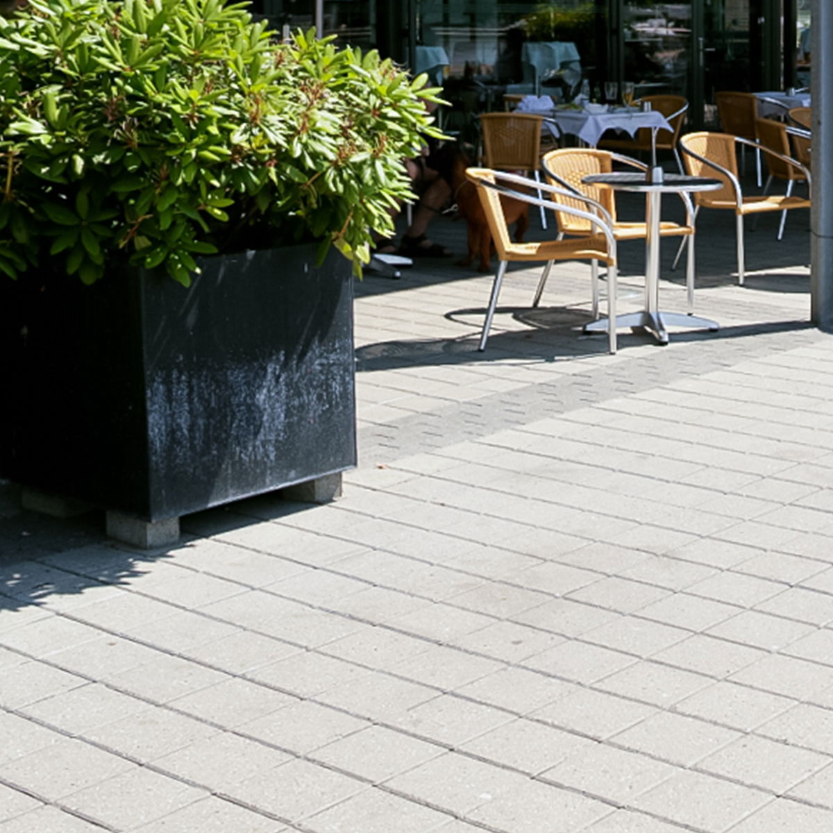 lysegrå ibf modulfliser 15x15 lagt som terrasse ved café med møbler.