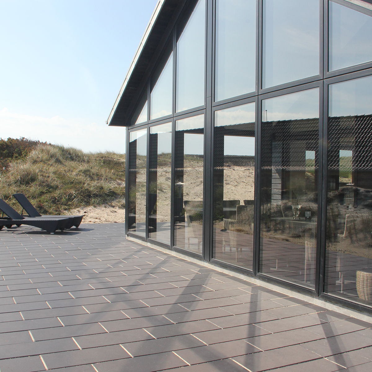 ibf sort plus fliser som terrasse ved moderne sommerhus med store vinduer.