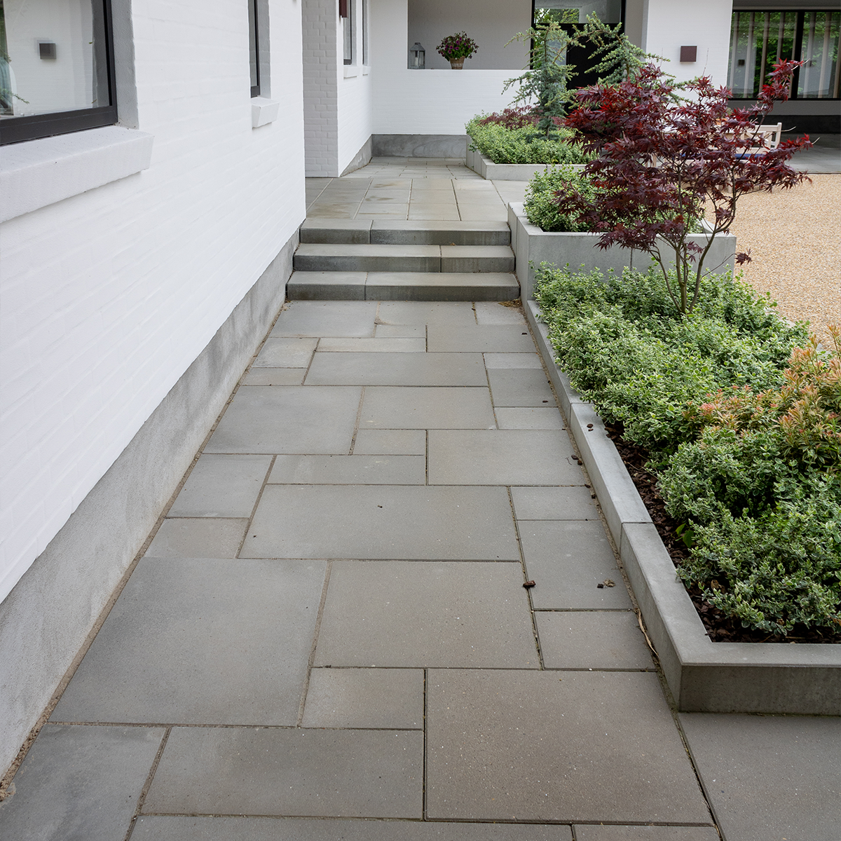 ibf modulfliser grå 25x50 lagt som sti op til hus med trappe og beplantning.