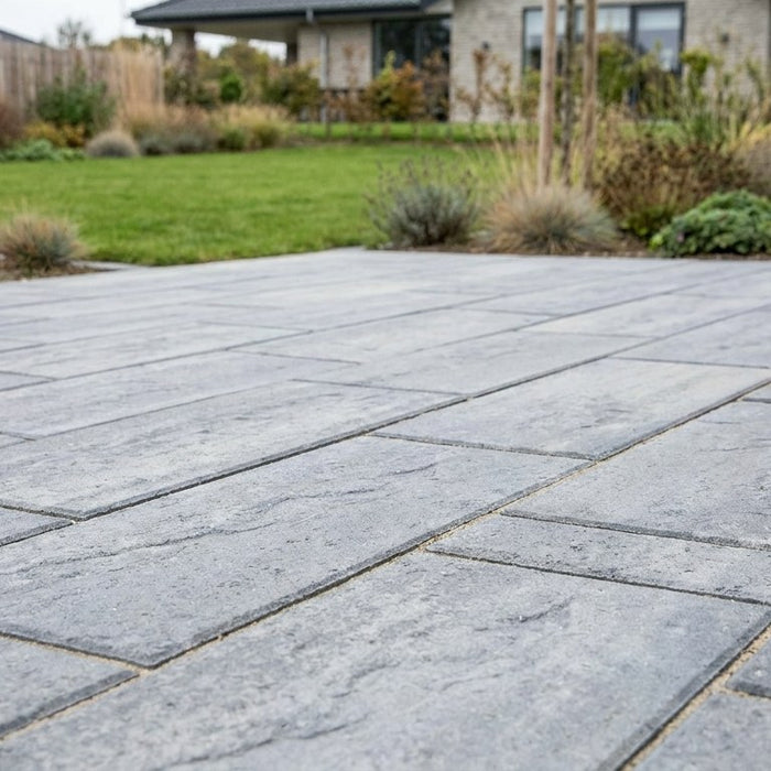 Nyanlagt moderne terrasse med store rektangulære 30x60 cm fliser i lys sandfarve, lagt i et elegant halvforbandt.