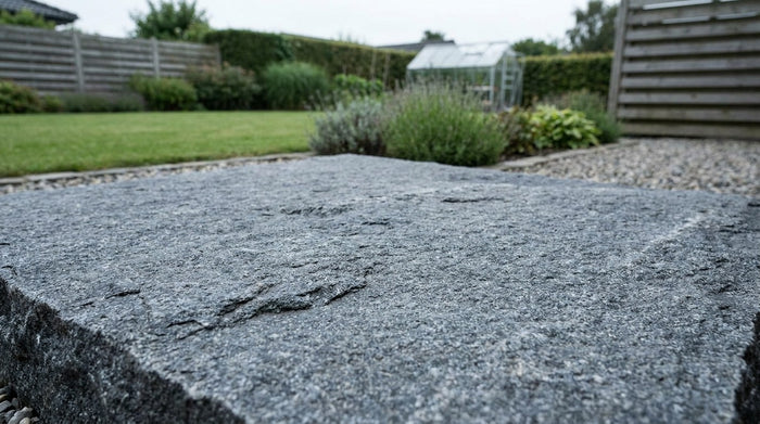 Nærbillede af en ru, jetbrændt granitflise lagt på en udendørs terrasse