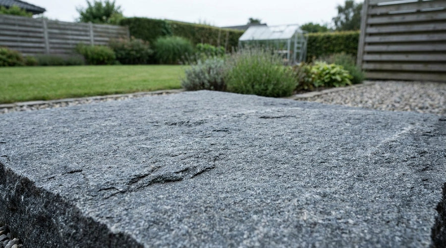 Nærbillede af en ru, jetbrændt granitflise lagt på en udendørs terrasse