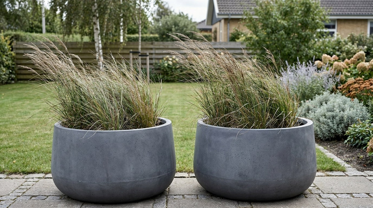 Store plantekummer beton anvendt som arkitektonisk rumdeler og læhegn på en moderne dansk terrasse