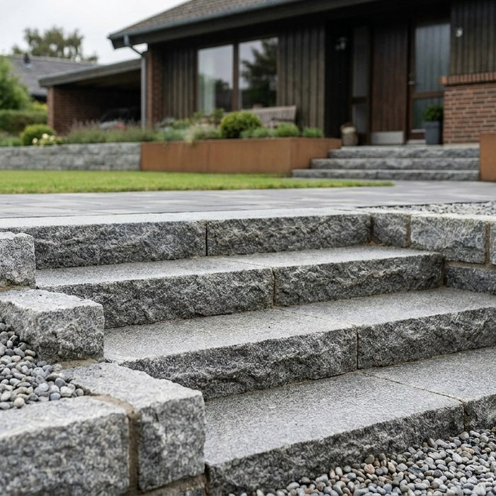 En nyanlagt, majestætisk udendørs granit trappe foran en dansk villa, omgivet af flot natursten og belægning.