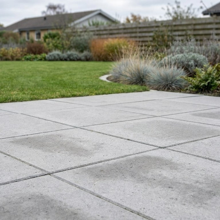 Nyanlagt terrasse bygget med klassiske og prisvenlige betonfliser, lagt i et flot mønster i en dansk have.