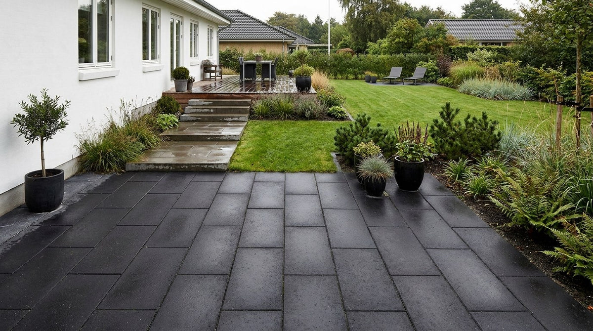 Nyanlagt terrasse med mørke IBF Sort Plus betonfliser, omkranset af grøn plæne