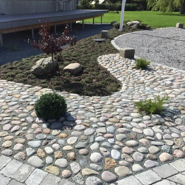 Pigstensbelægning i have med beplantning. Romantisk bondehavestil.