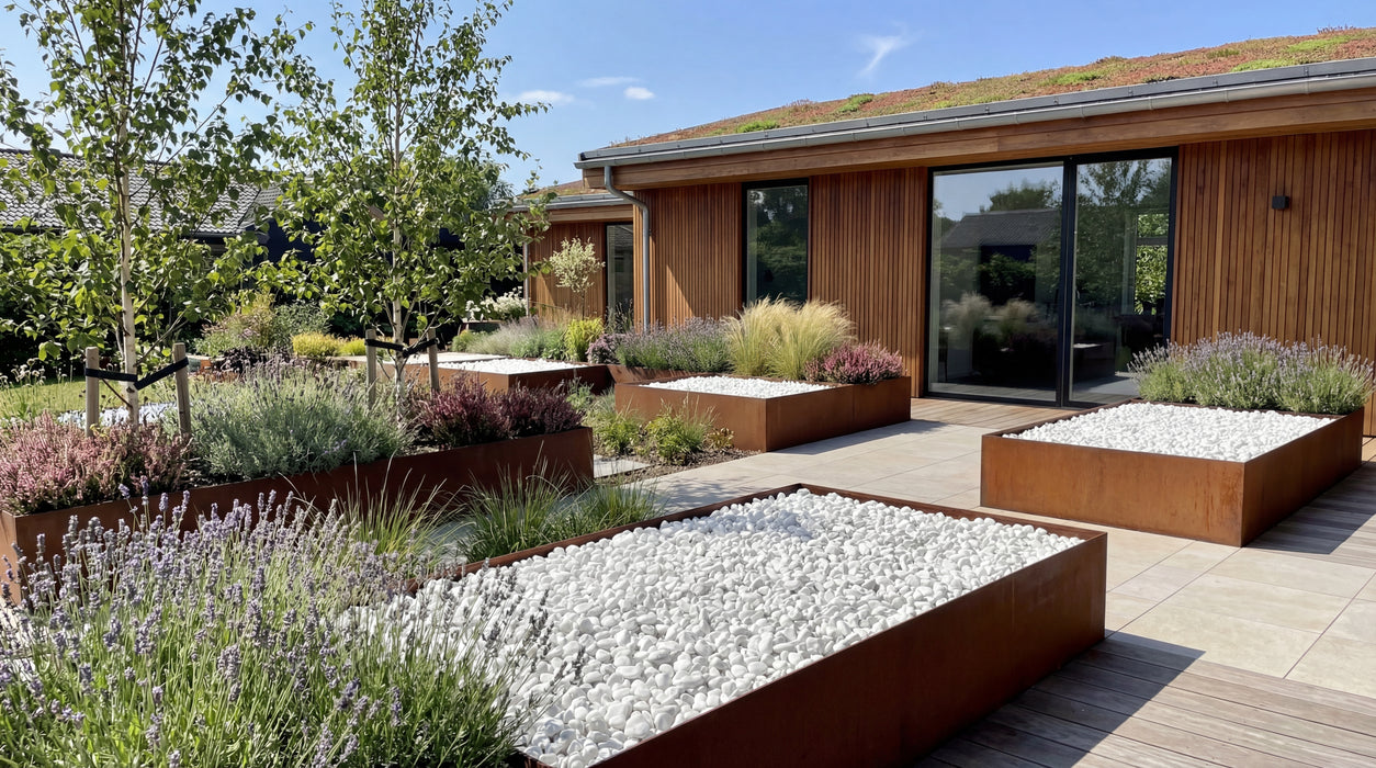 hvide marmorsten i højbede af cortenstål, set i havemiljø.