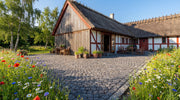 sorte halve chaussesten som belægning ved stråtækt hus og blomsterbed