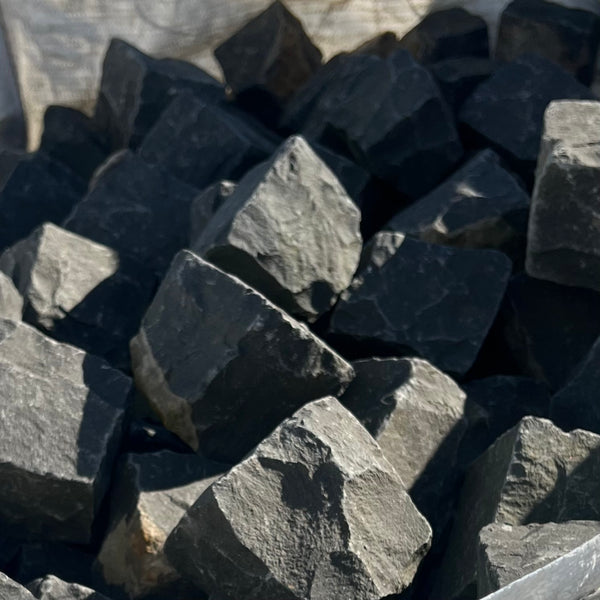 bunt af brugte, sorte basalt chaussesten i forskellige størrelser.