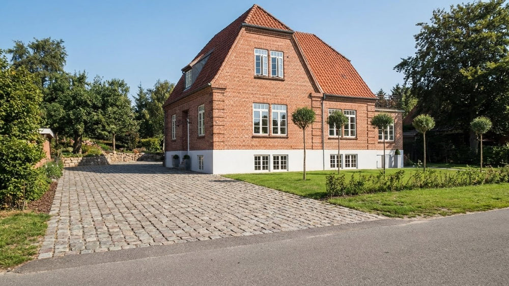 indkørsel belagt med grålige chaussesten, mix af nye og slidte sten.