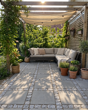 Lysegrå kløvede chaussesten mellem terrassefliser ved pergola