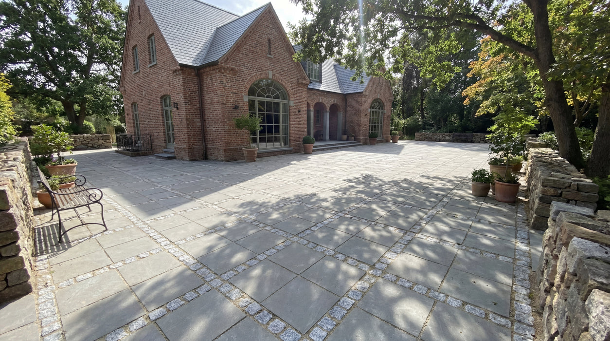 store grå ibf betonfliser (40x40) med småsten som fuger på gårdsplads.