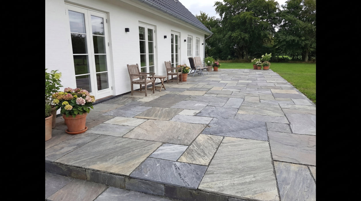 terrasse med dark sandsten i romersk mønster ved hvidt hus